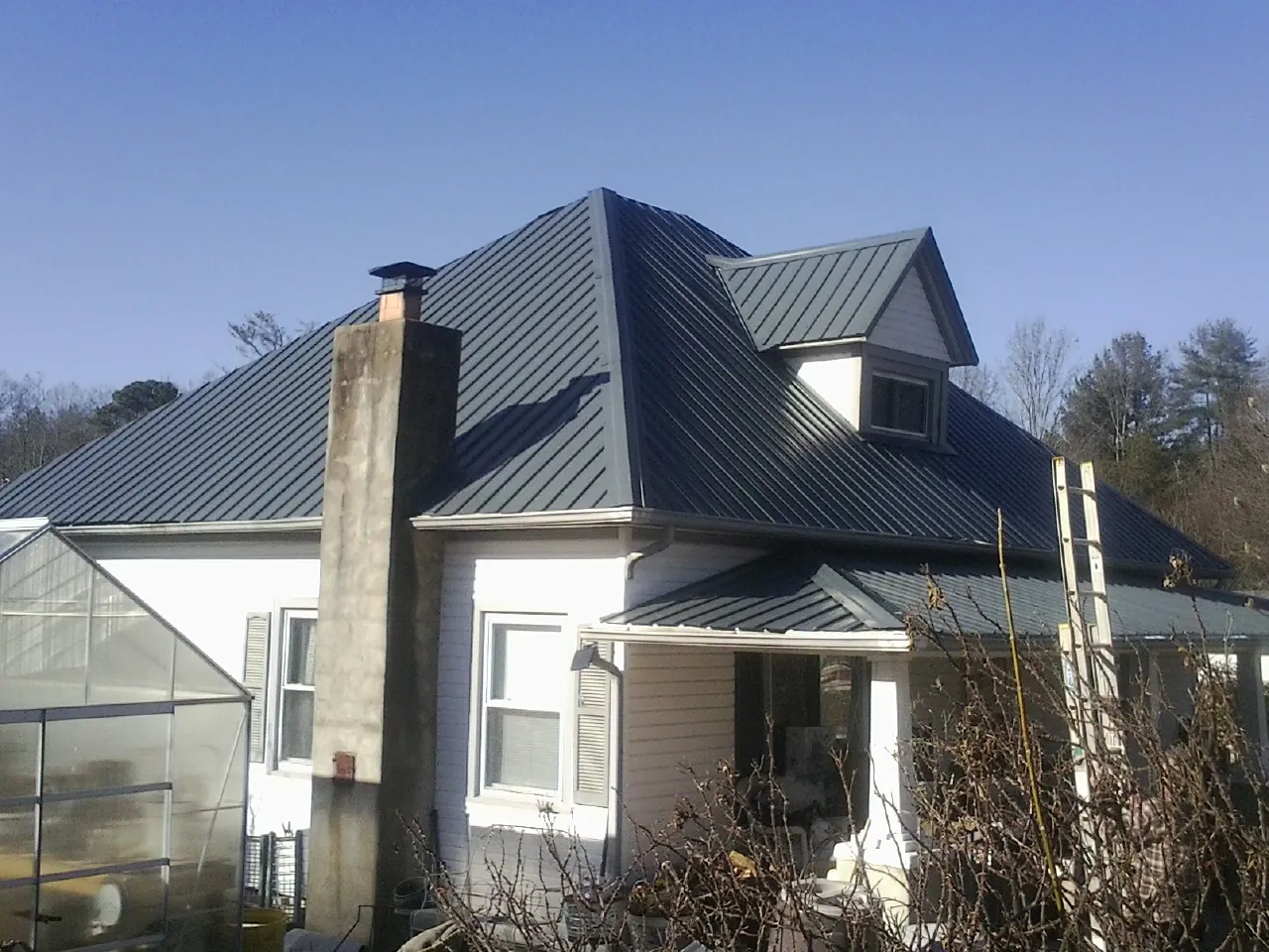 Dark blue standing seam metal roof on a white farmhouse with dormer — Slate & Tile Roof Repair by Roofing Brothers in Feasterville Trevose