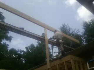 Carpenter setting a ridge beam over a new addition frame — Ice Dam Removal by Roofing Brothers in Feasterville Trevose