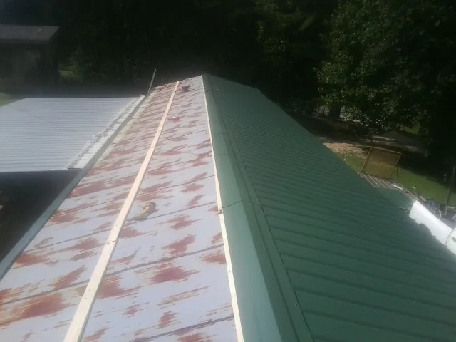Old rusted panels beside newly installed green metal roofing — Wind Damage Roof Repair by Roofing Brothers in Feasterville Trevose