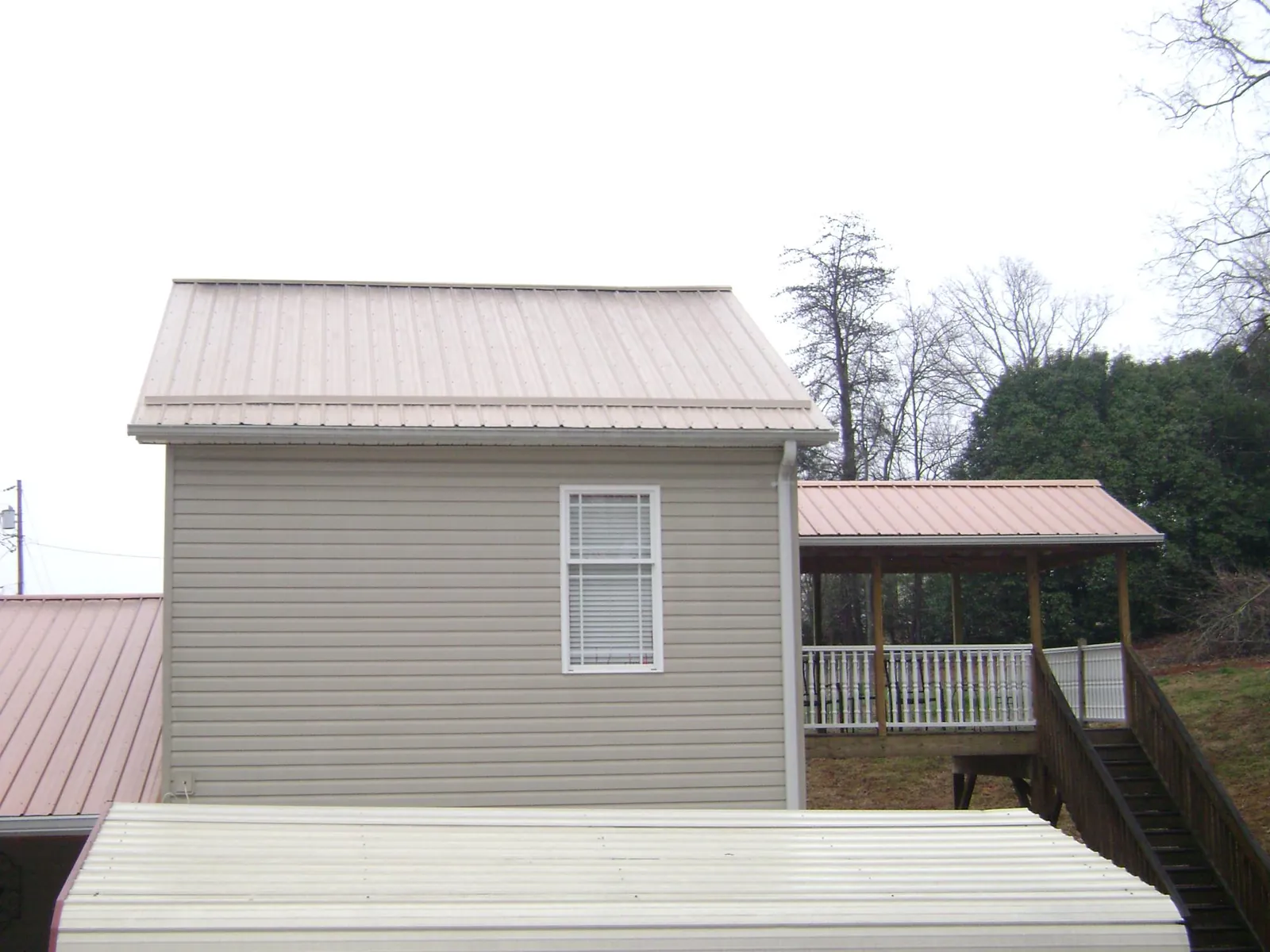 Tan metal roofs on a two story addition and attached porch, from a Roof Replacement job in Feasterville Trevose